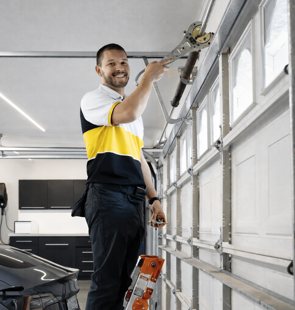 Garage door technician on a ladder servicing an overhead garage door